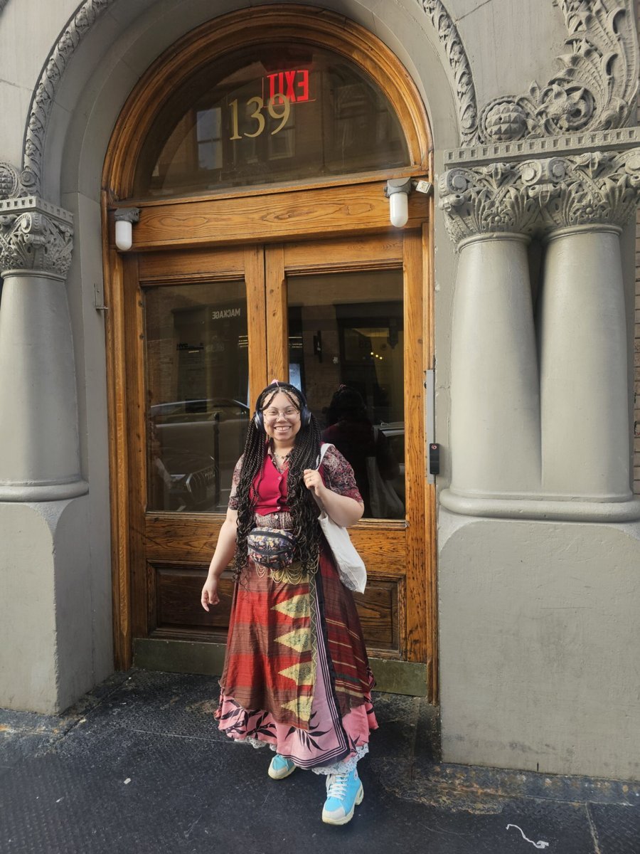 Alora smiling in front of an arched wooden doorway
